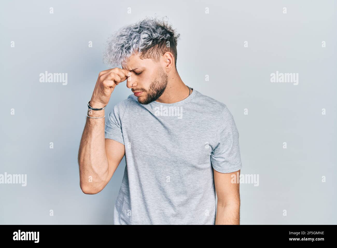 Jeune homme hispanique avec des cheveux teints modernes portant décontracté  t-shirt gris fatigué frottant nez et yeux sensation de fatigue et de maux  de tête. Stress et frustration Photo Stock - Alamy