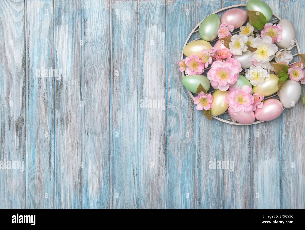 Œufs de Pâques avec décoration florale sur fond bleu en bois Banque D'Images