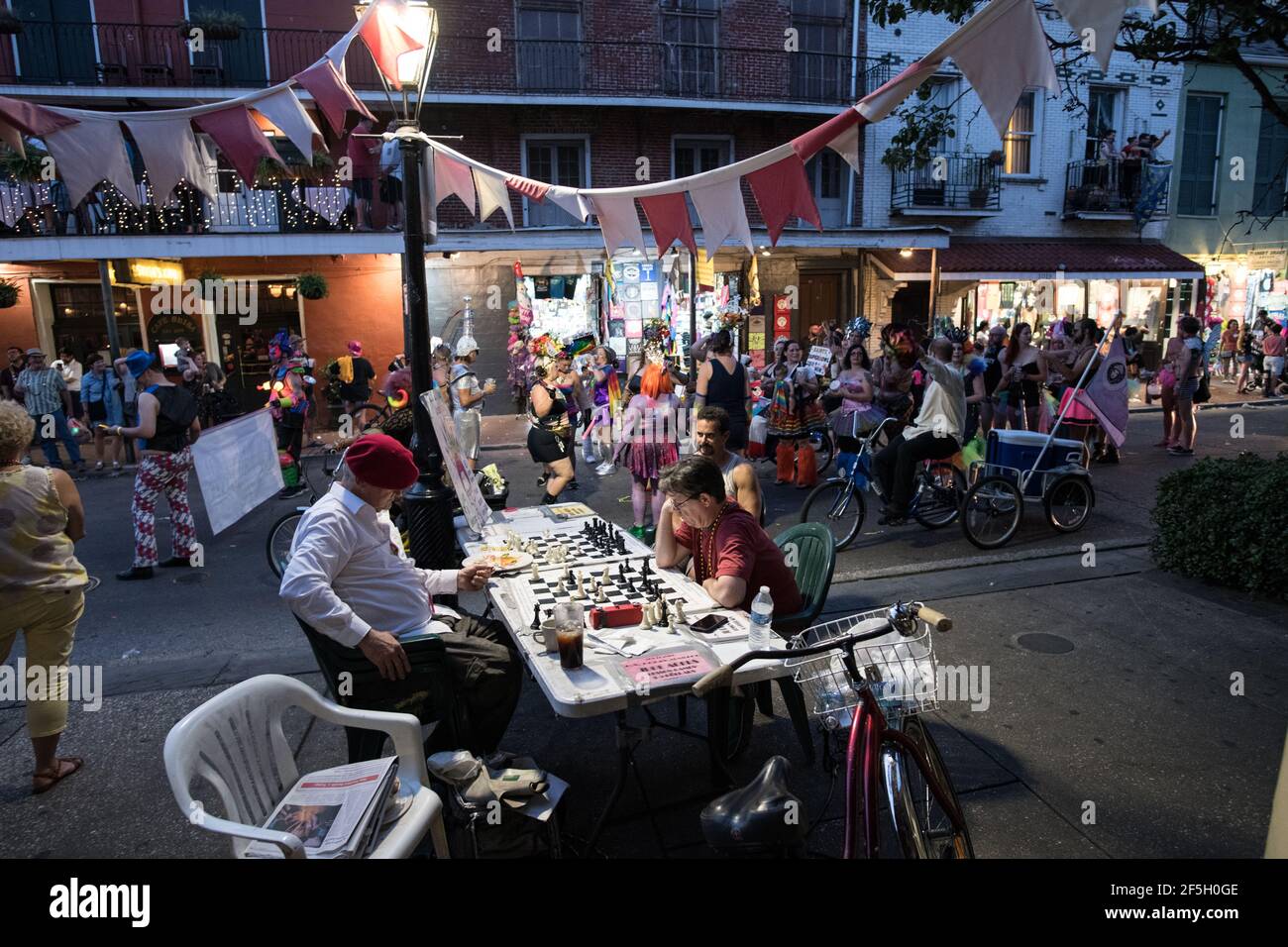 Jude Acers, maître d'échecs, joue un jeu sur Decatur Street dans le quartier français alors qu'un défilé passe devant, capturant l'esprit dynamique de la Nouvelle-Orléans. Banque D'Images