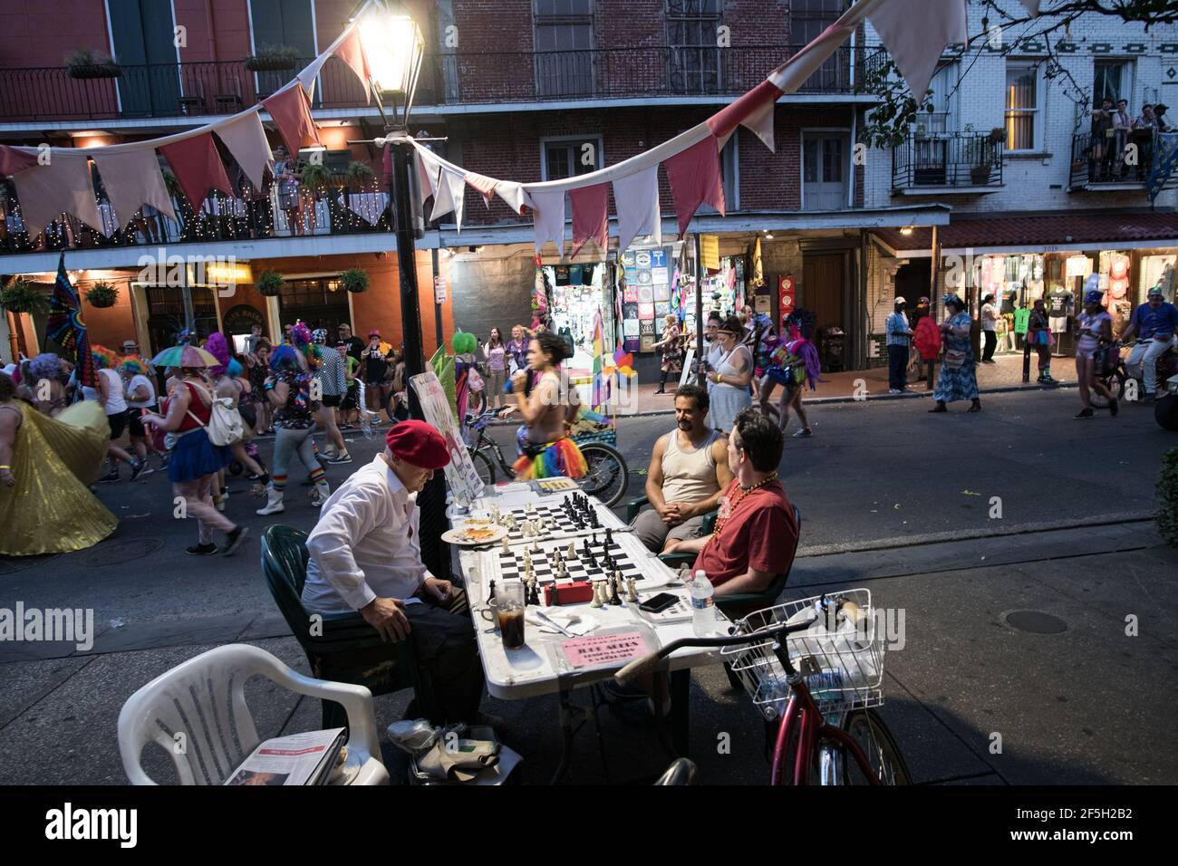 Jude Acers, maître d'échecs, joue un jeu sur Decatur Street dans le quartier français alors qu'un défilé passe devant, capturant l'esprit dynamique de la Nouvelle-Orléans. Banque D'Images
