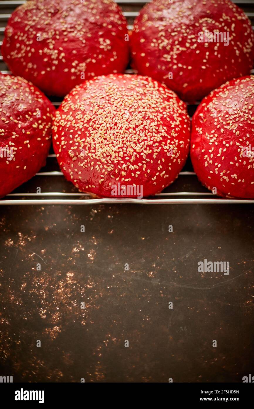 Petits pains à hamburger faits maison, rouges et frais, avec vue sur le dessus du sésame. Placé sur la grille métallique. Banque D'Images