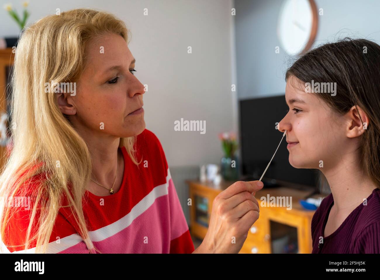 Test rapide de l'antigène Corona, test de pose, auto-test, pour détecter l'infection par le COV-SRAS, la mère prélève un échantillon de sa fille, écouvillon nasal, Banque D'Images