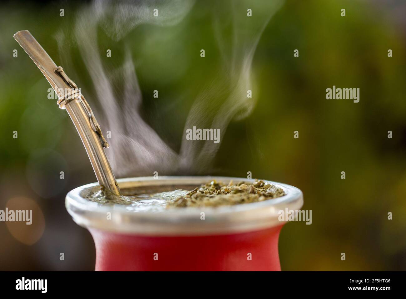 Gros plan horizontal de la chaude traditionnelle sud-américaine, Caffeine-Rich Infused Drink Mate (Yerba Mate) dans le Gourd de céramique rouge. Perfusion du compagnon de cuisson à la vapeur Banque D'Images