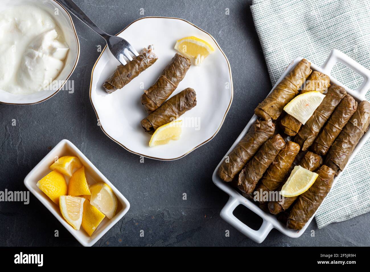 Le Yaprak sarmasi est un plat turc traditionnel fait en enveloppant le farce de riz avec des feuilles de raisin. Servi dans un plateau en porcelaine avec des tranches de citron et une tasse de Banque D'Images