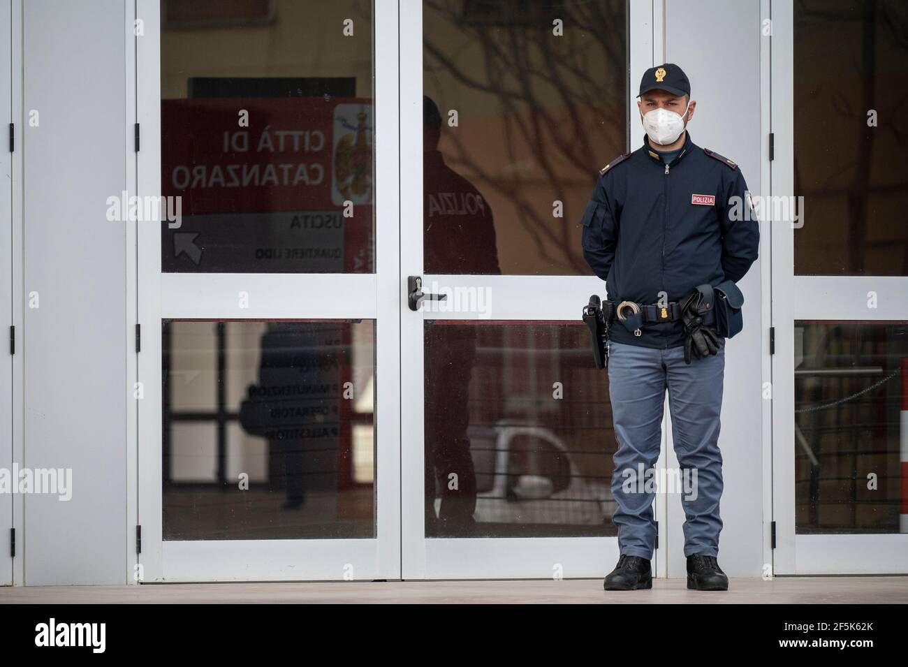 Un policier vu debout devant la porte d'entrée. Le Lieutenant général Francesco Paolo Figliuolo, récemment nommé commissaire extraordinaire pour l'urgence COVID-19, et Fabrizio Curcio, Chef du Département de la protection civile, ont visité de nouveaux centres de vaccination en Calabre. À Catanzaro, dans le quartier de bord de mer "Lido", ils ont visité le nouveau centre des expositions choisi comme centre potentiel. Sergio Abramo, maire de Catanzaro, et Antonino Spirlì, et gouverneur régional temporaire, les ont guidés pendant la visite. L'augmentation des centres de vaccination est considérée comme une priorité, particulièrement en considération Banque D'Images