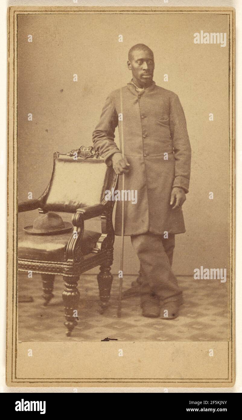 Soldat noir debout près d'une chaise avec un chapeau assis. Alexander Gardner (américain, né en Écosse, 1821 - 1882) Banque D'Images