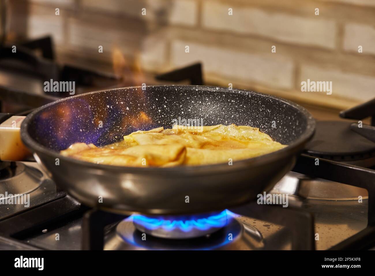 Cuisine à la maison dans la cuisine selon la recette de l'Internet. Les crêpes sont frites dans une poêle avec l'ajout d'alcool - en mousse. Étape par étape Banque D'Images