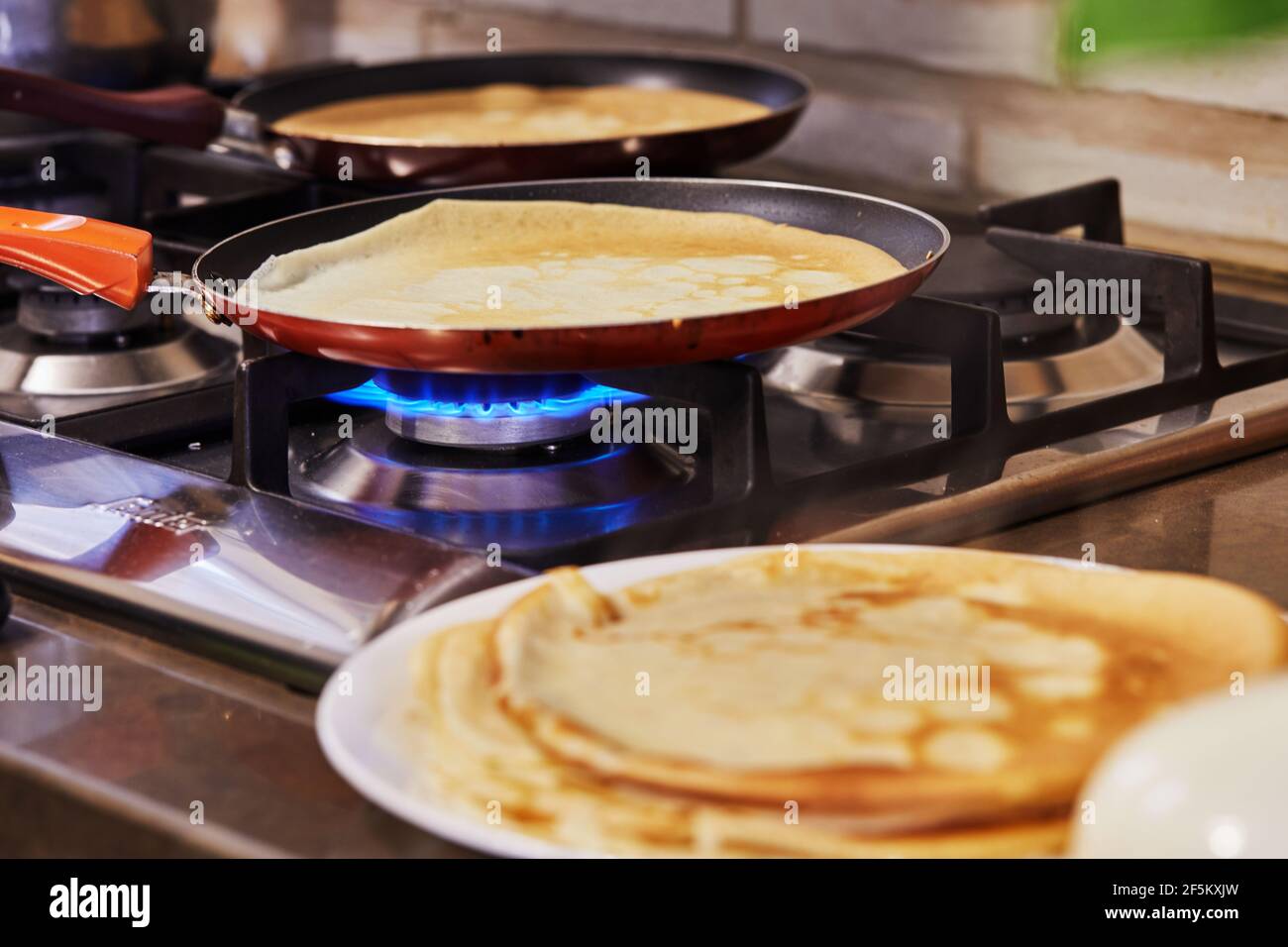 Cuisine à la maison dans la cuisine selon la recette de l'Internet. Les crêpes sont frites dans des casseroles sur un four à gaz. Recette étape par étape. Banque D'Images
