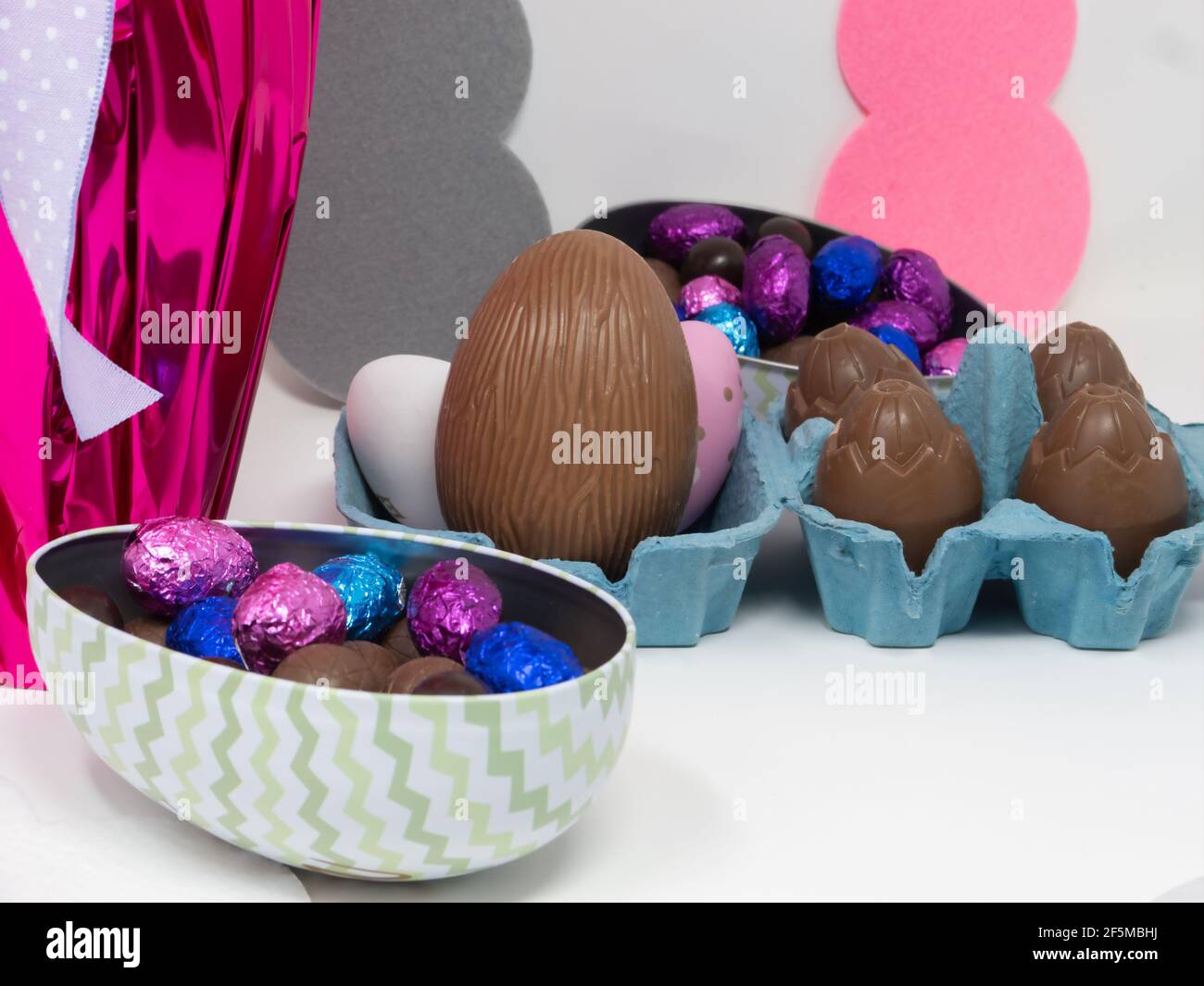 Œufs de chocolat de Pâques de différentes tailles sur fond blanc avec silhouettes de lapin Banque D'Images