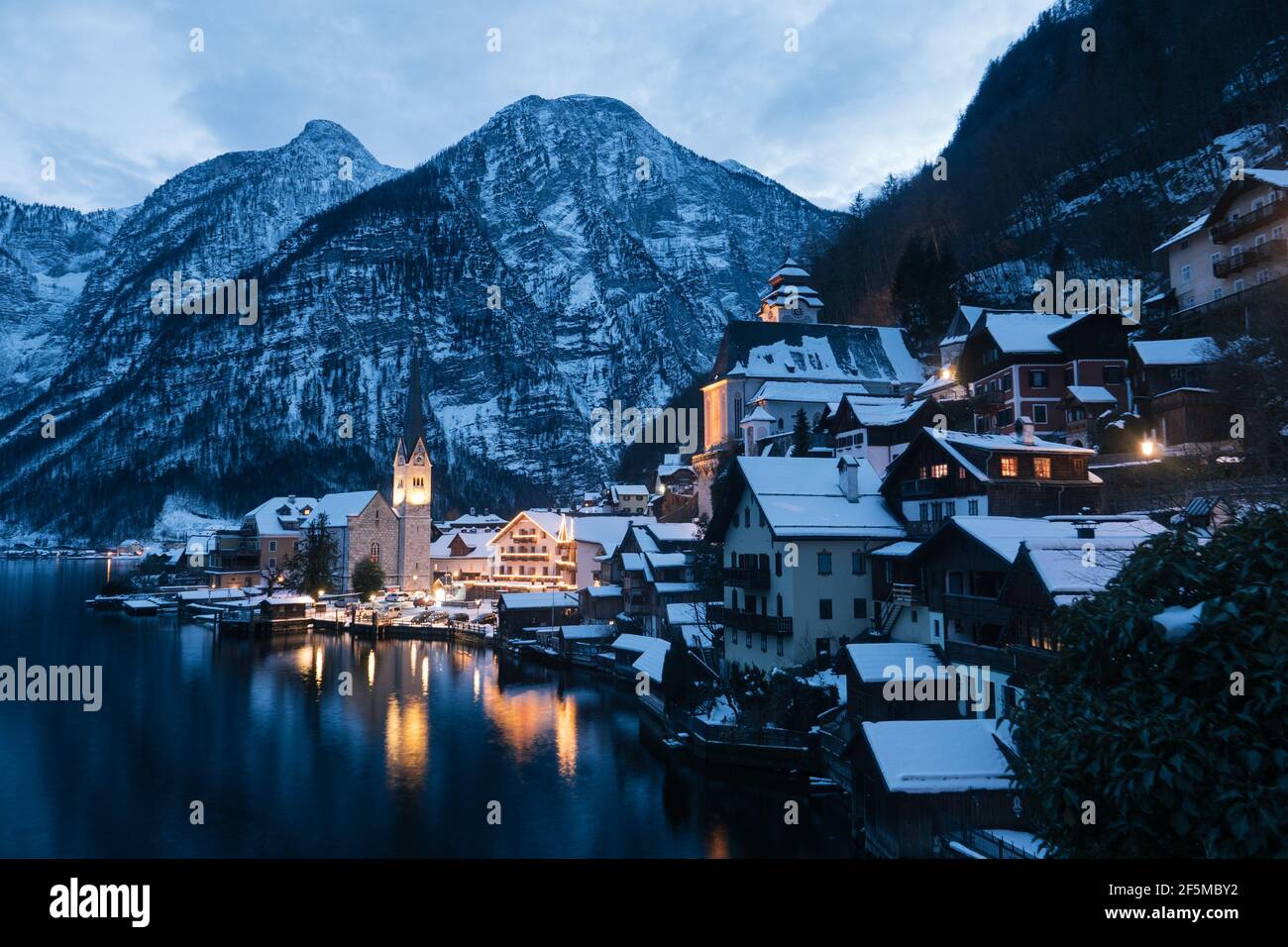 Hallstatt CityScape lors d'une soirée d'hiver froide couverte de neige Avec le lac Hallstaetter Voir et l'église illuminée la nuit Banque D'Images