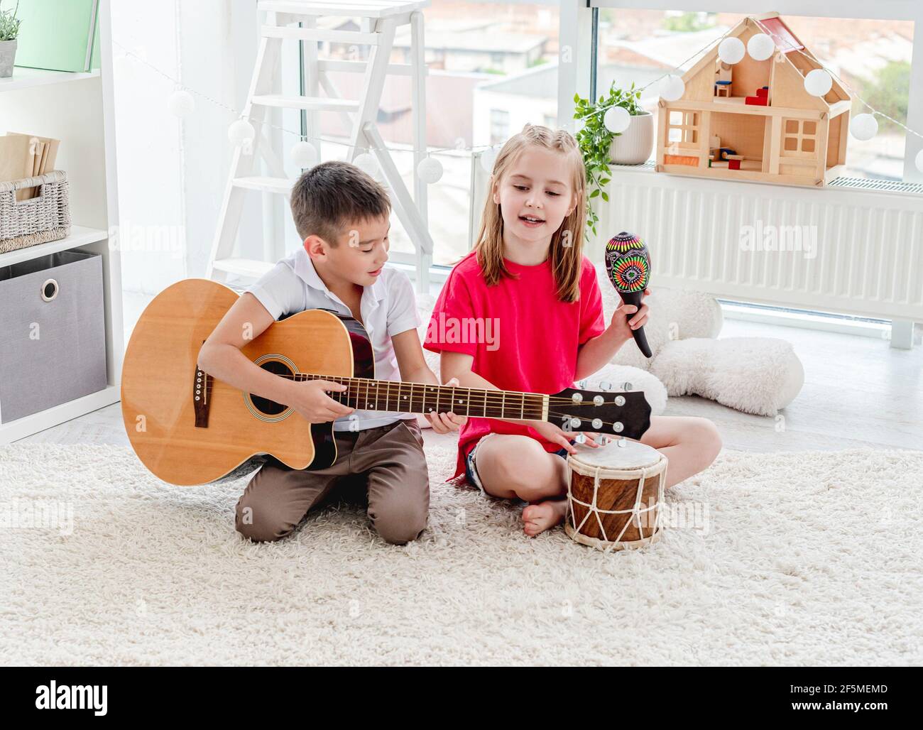 Des enfants souriants jouant sur le tambour et la guitare Banque D'Images