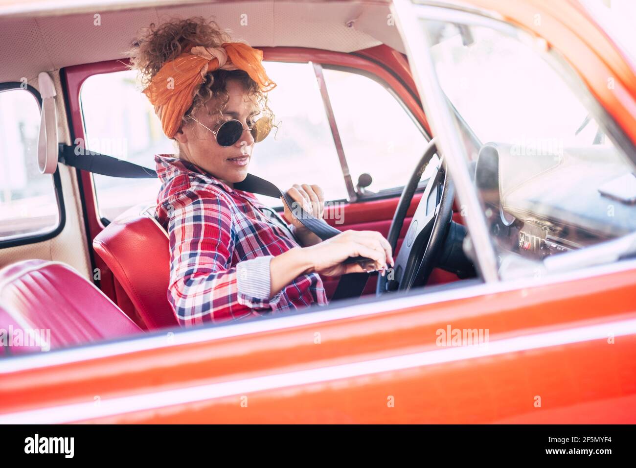 Femme tenant la ceinture de sécurité à l'intérieur de la voiture vue de extérieur - concept d'assurance et de chauffeur de femme - jeune jeune femme tendance aime voyager Banque D'Images