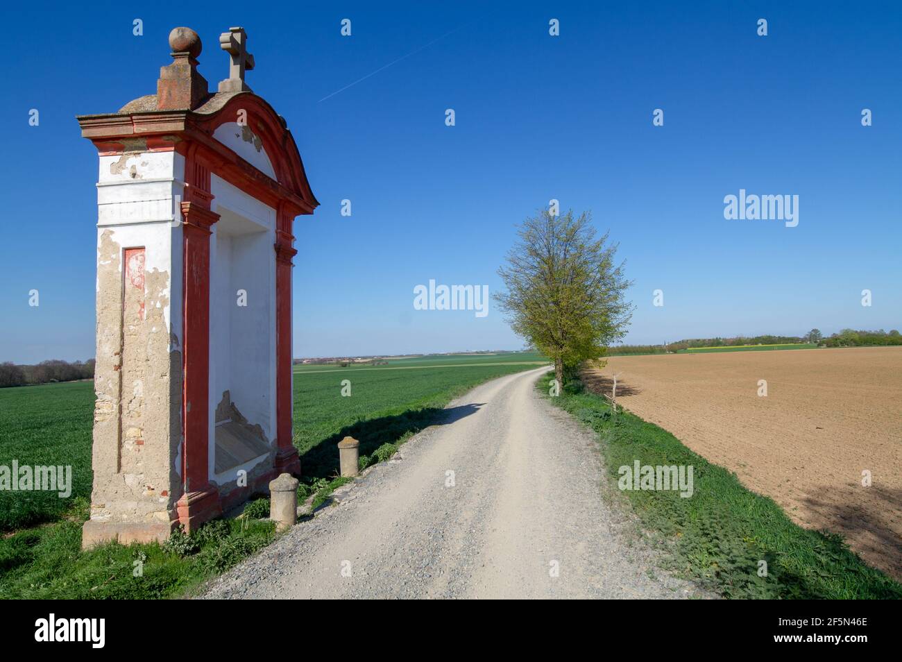 20ème chapelle de Hájecká chemin de pèlerinage près de Prague, une chapelle baroque en alcôve située près d'une route de campagne lors d'une journée de printemps claire. Banque D'Images