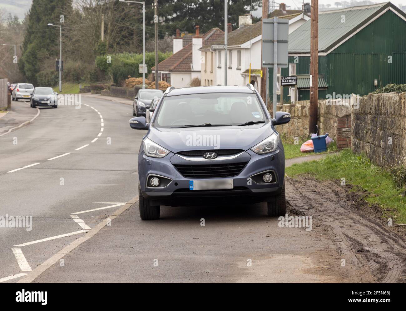 Voiture garée sur la chaussée bloquant la circulation à pied et obligeant les gens à marcher sur la route ou la boue, pays de Galles, Royaume-Uni Banque D'Images