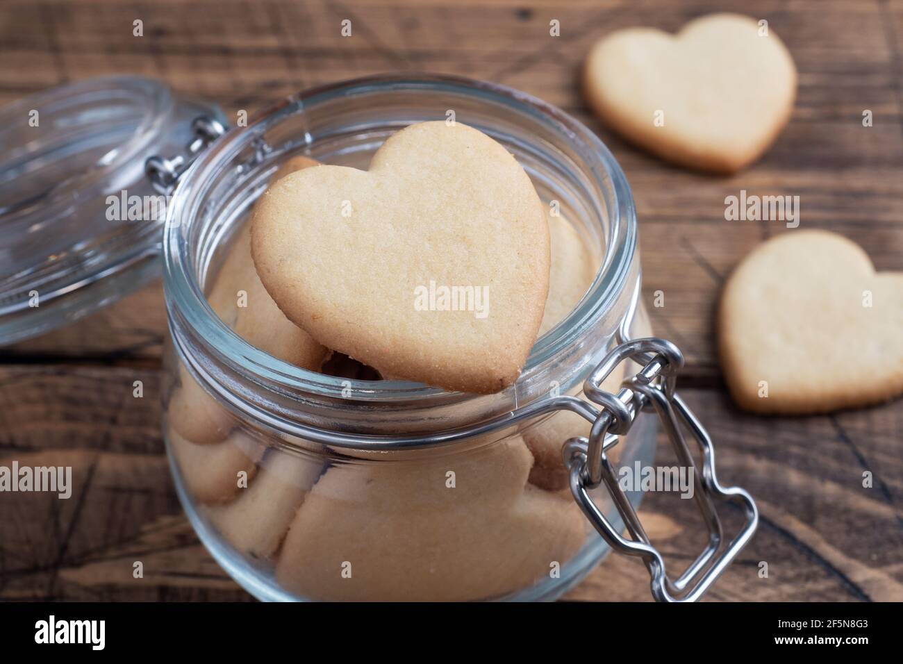 Biscuits faits maison en forme de coeur dans un pot en verre, fond en bois. Le concept de la Saint-Valentin Banque D'Images Biscuits faits maison en forme de coeur dans un pot en verre, fond en bois. Le concept de la Saint-Valentin Banque D'Images