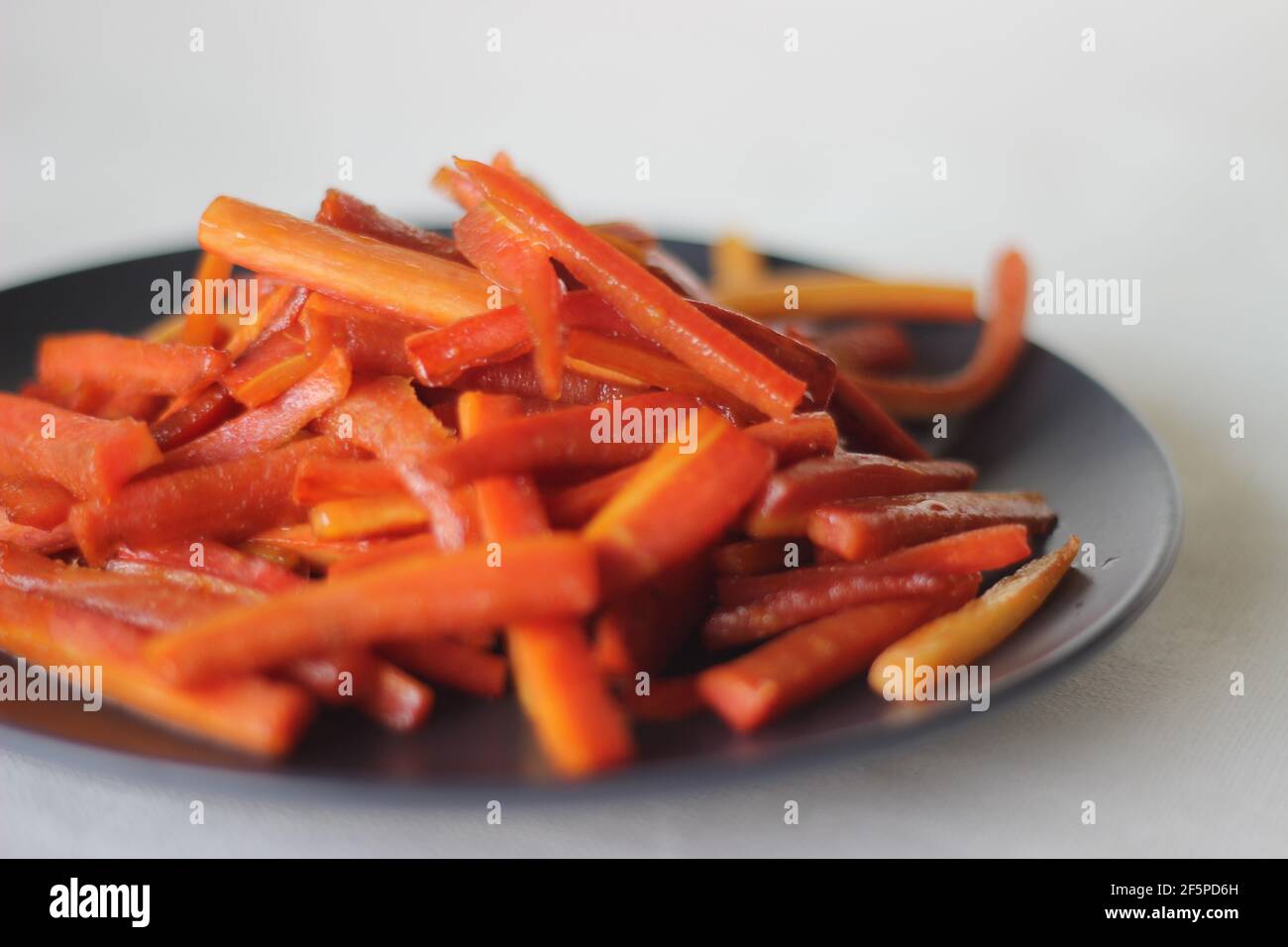 Bâtonnets de carottes caramélisés. Les carottes sautées avec du beurre et du sucre. Une collation rapide et saine. Prise de vue sur fond blanc Banque D'Images