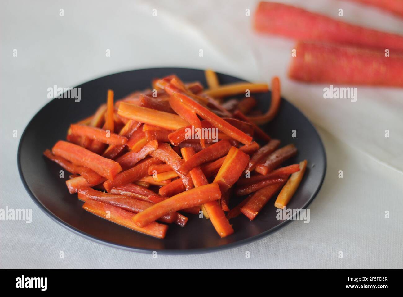 Bâtonnets de carottes caramélisés. Les carottes sautées avec du beurre et du sucre. Une collation rapide et saine. Prise de vue sur fond blanc Banque D'Images