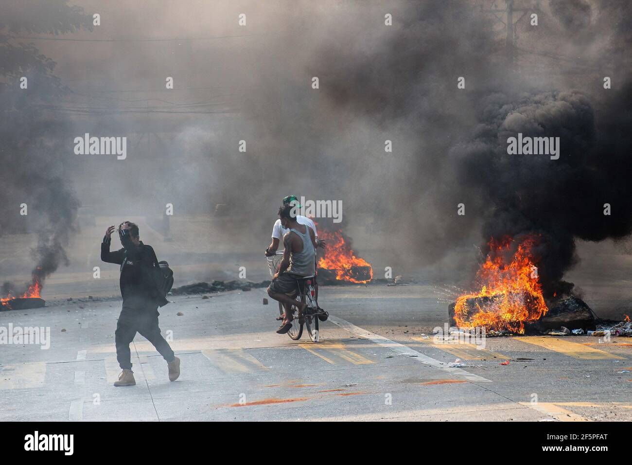 Un homme passe devant des pneus en feu dans la rue lors d'une manifestation contre le coup d'Etat militaire.la police et les militaires du Myanmar (tatmadow) ont attaqué les manifestants avec des balles en caoutchouc, des munitions réelles, des gaz lacrymogènes et des bombes lacrymogènes en réponse aux manifestants anti-coup d'Etat militaire de samedi, tuant plus de 90 personnes et en blessant beaucoup d'autres. Au moins 300 personnes ont été tuées au Myanmar depuis le coup d'État du 1er février, a déclaré un responsable des droits de l'homme de l'ONU. L'armée du Myanmar a détenu le conseiller d'État du Myanmar Aung San Suu Kyi le 01 février 2021 et a déclaré l'état d'urgence tout en prenant le pouvoir dans le Banque D'Images