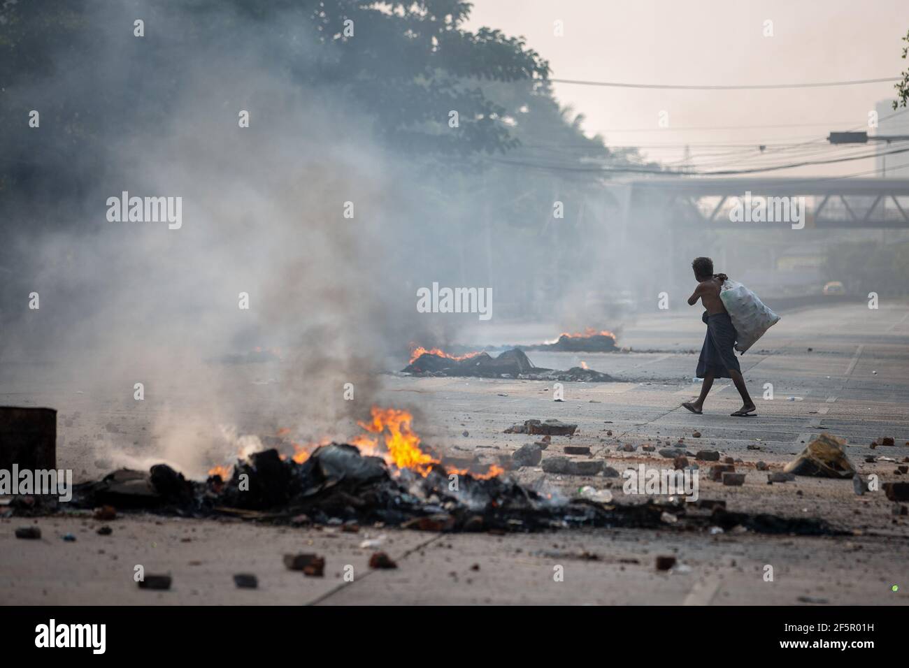 Yangon, Myanmar. 27 mars 2021. Un préparateur de bouteilles passant par les pneus en feu pendant la démonstration. L'armée birmane attaque les manifestants avec des balles en caoutchouc, des munitions réelles, des gaz lacrymogènes et des bombes sonores en réponse. Le nombre de morts pour aujourd'hui est de 144 et le plus élevé depuis le coup d'État militaire du 1er février. (Photo de Theint mon SOE/SOPA Images/Sipa USA) Credit: SIPA USA/Alay Live News Banque D'Images