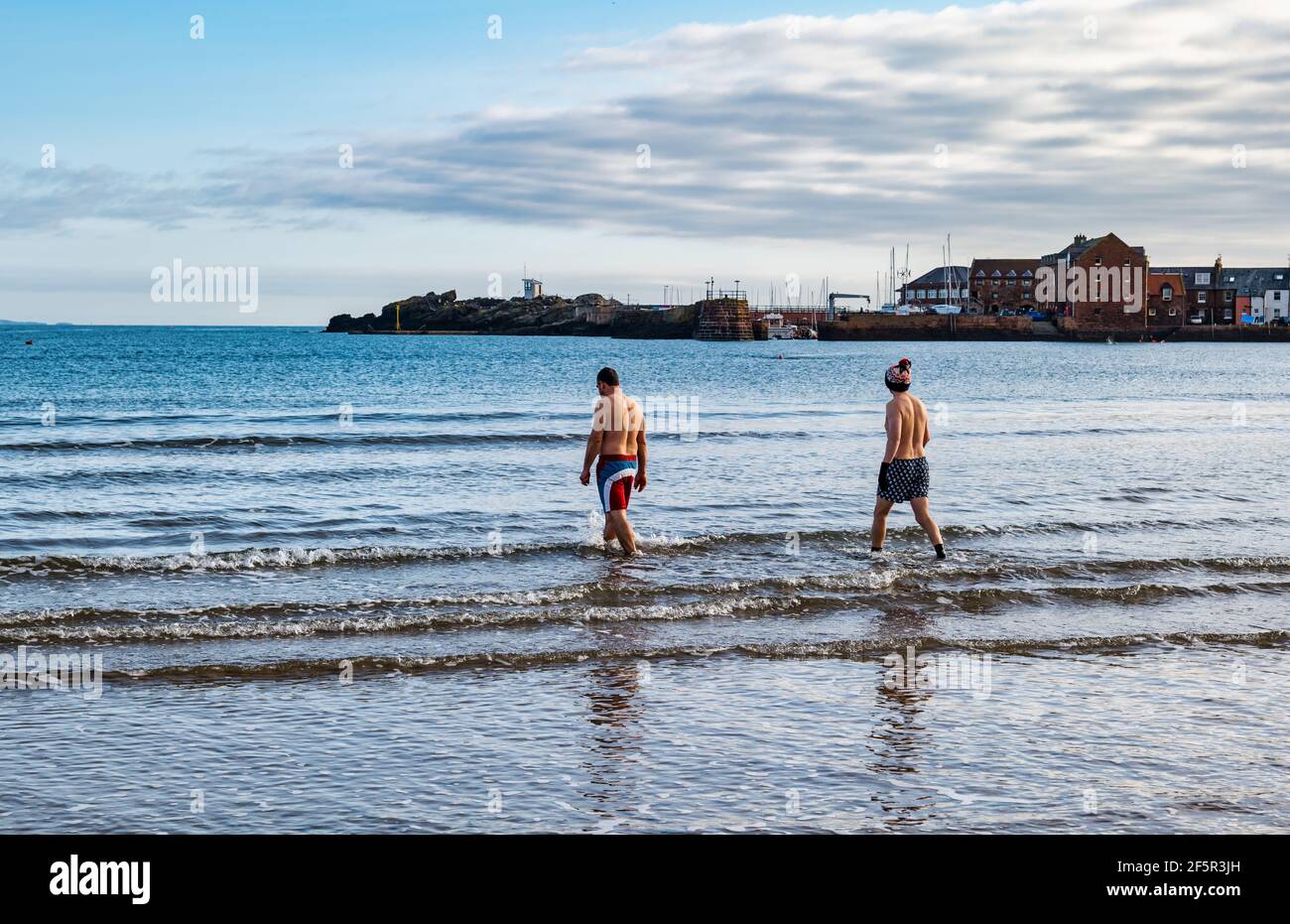 Deux nageurs d'eau libre ou sauvage de sexe masculin portant des troncs de natation entrent dans le Firth of Forth Sea à West Bay, North Berwick, East Lothian, Écosse, Royaume-Uni Banque D'Images