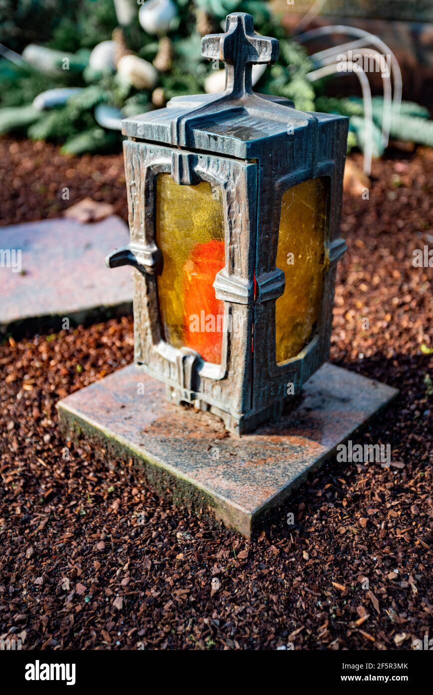 lumière grave endommagée avec bougie allumée sur une tombe Banque D'Images