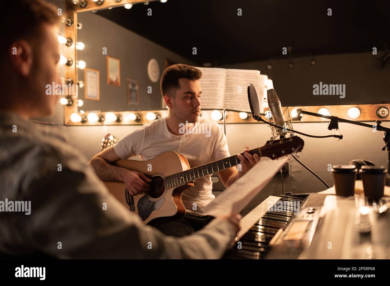 Guitariste masculin créant une chanson avec un ami Banque D'Images