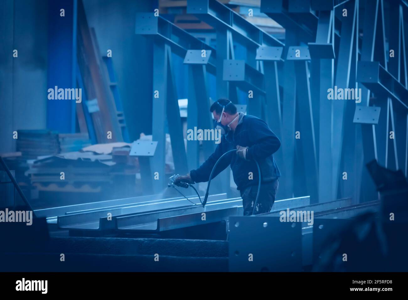 Homme avec masque de protection peinture et laquage d'acier avec compresseur Banque D'Images