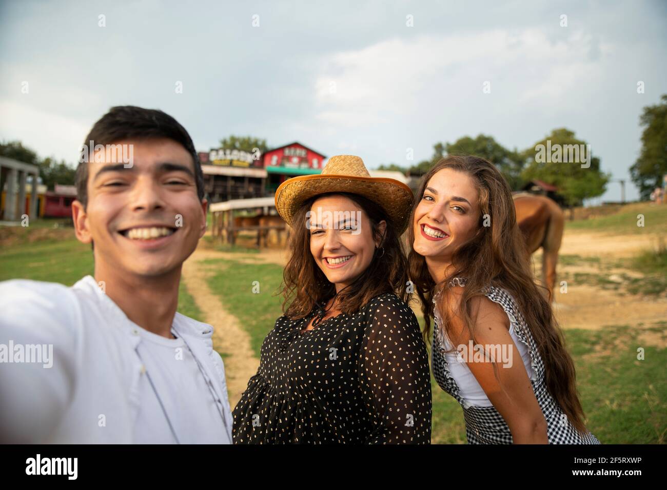 Trois amis utilisant Smart Phone pour la photographie avec les chevaux dans le Ranch. Jour d'été Banque D'Images