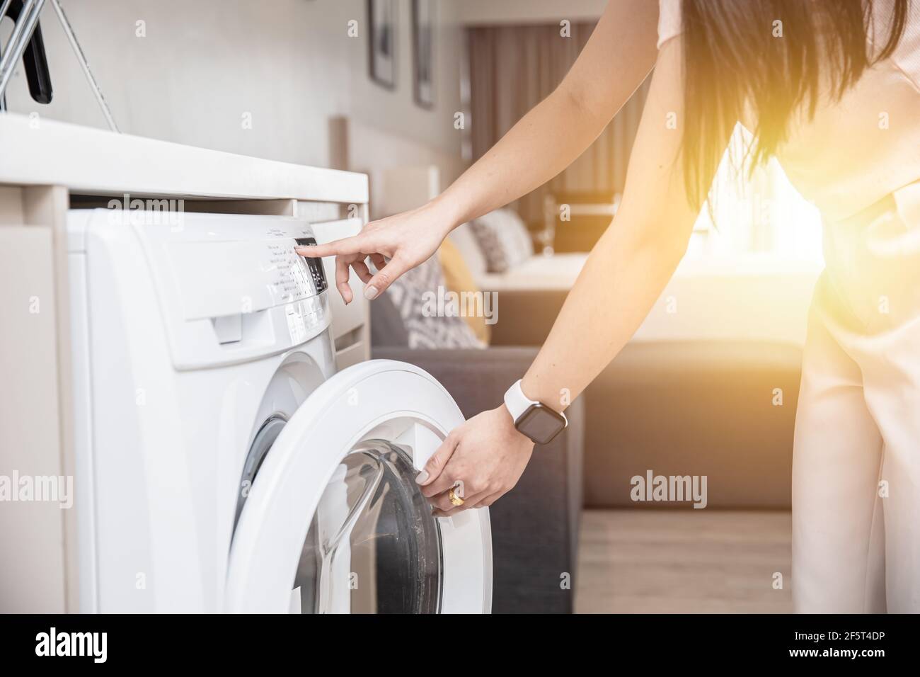 Femme au foyer utilisant la machine à laver à la maison le matin. Banque D'Images