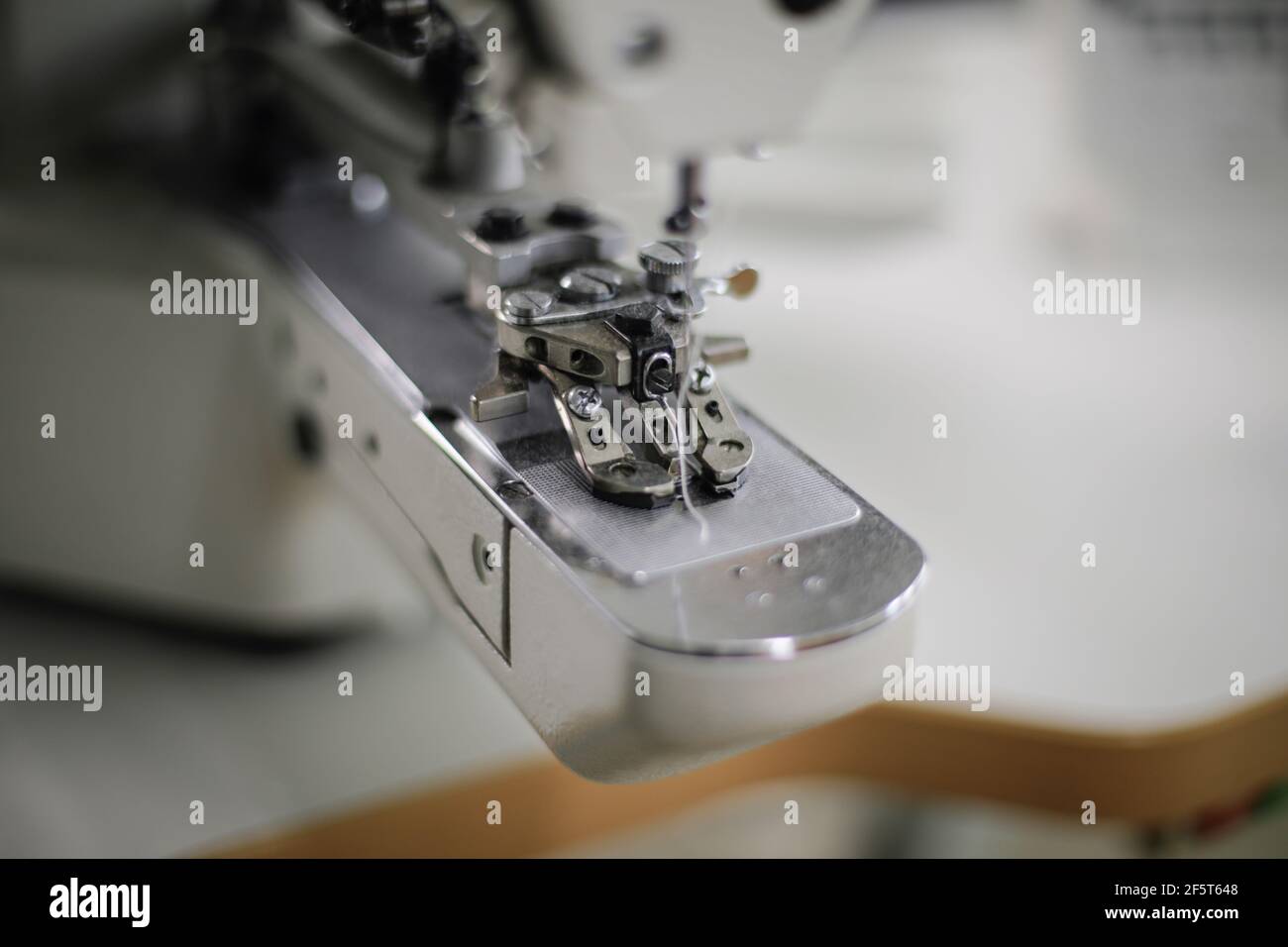 Image de faible profondeur de champ (mise au point sélective) avec une machine à coudre électrique dans une usine de textile. Banque D'Images