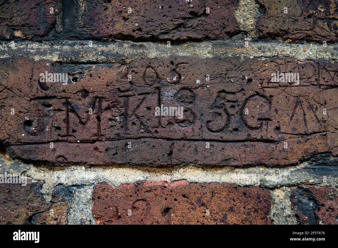 Des sculptures de chiffres, de lettres et de dates se creusent dans la brique d'un mur qui ligne d'un côté du passage Myddelton à Islington, dans le nord de Londres. Le curieux cas de vandalisme a probablement été effectué par les 19 et 20 officiers de police affectés à la garde du passage la nuit. Date de la photo : vendredi 26 mars 2021. Banque D'Images