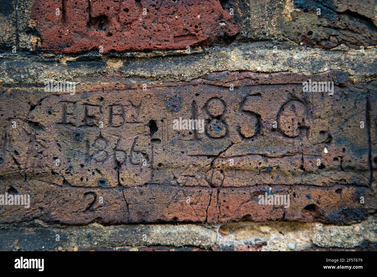 Des sculptures de chiffres, de lettres et de dates se creusent dans la brique d'un mur qui ligne d'un côté du passage Myddelton à Islington, dans le nord de Londres. Le curieux cas de vandalisme a probablement été effectué par les 19 et 20 officiers de police affectés à la garde du passage la nuit. Date de la photo : vendredi 26 mars 2021. Banque D'Images