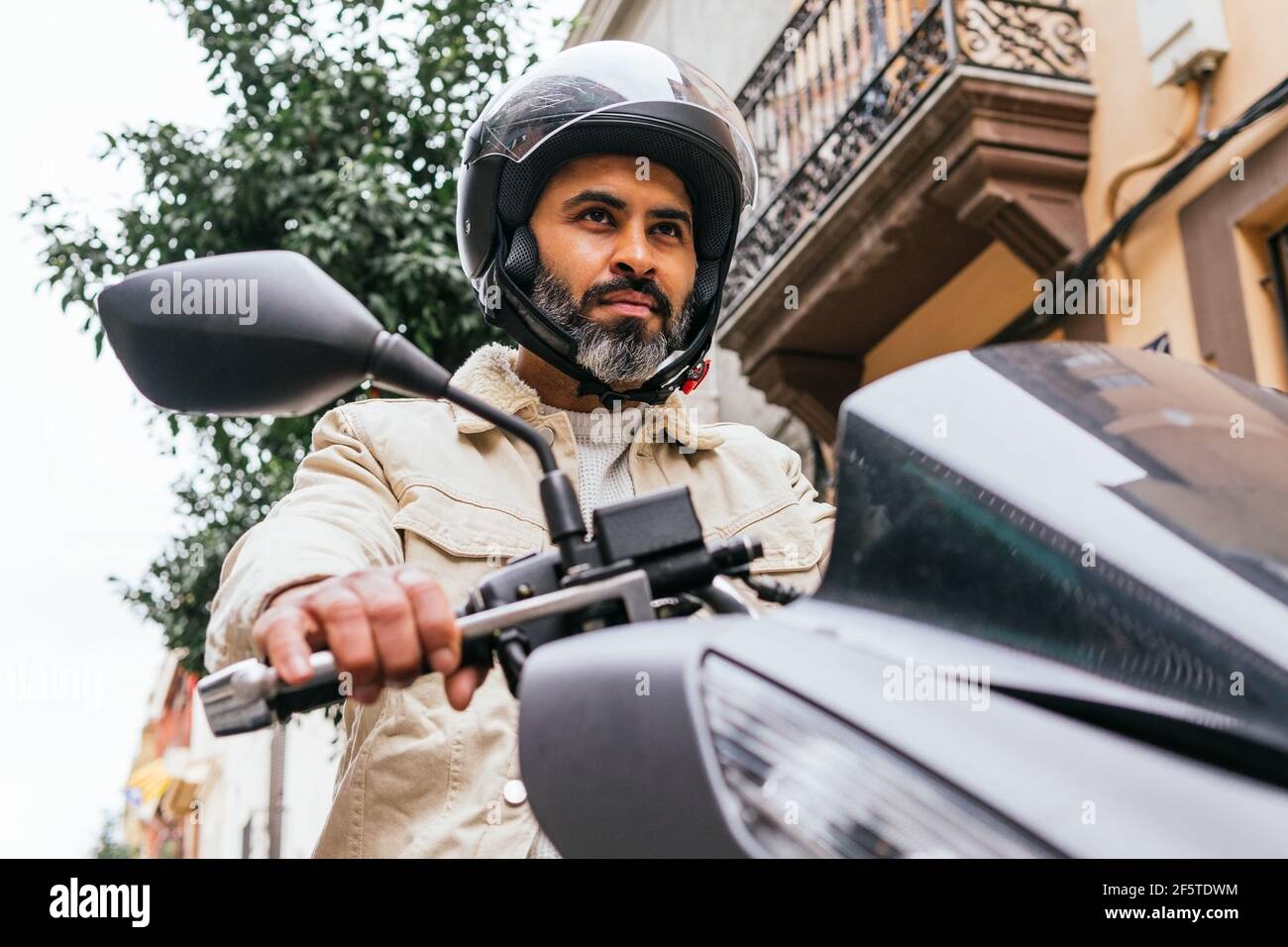 De dessous de la violente ethnie motard masculin dans la conduite de casque moto contemporaine avec vue sur la ville Banque D'Images