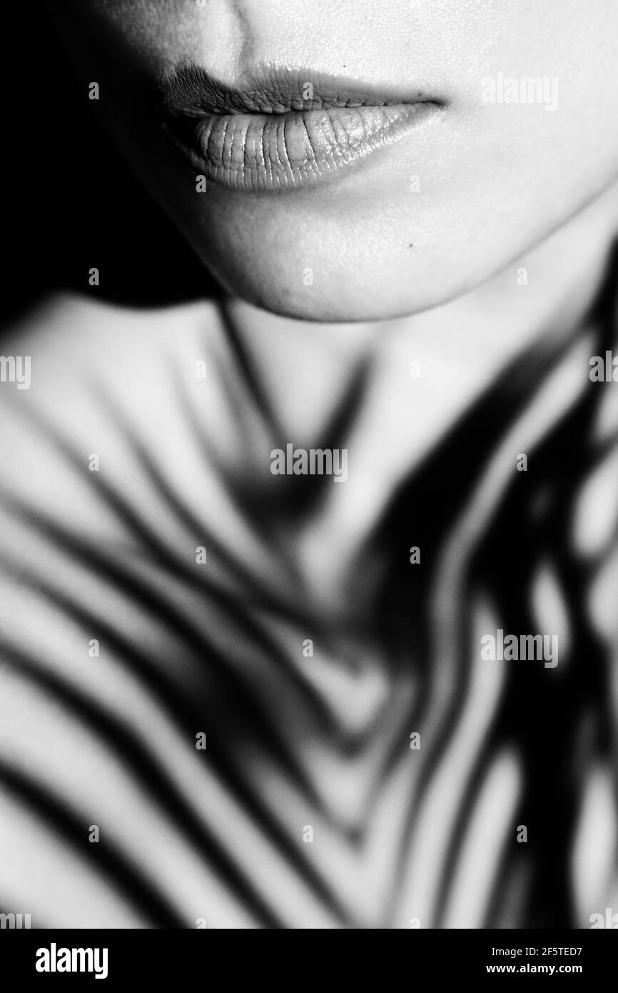 Noir et blanc de récolte anonyme tendre femelle avec maquillage sur les lèvres et à l'ombre sur la poitrine en plein soleil Banque D'Images