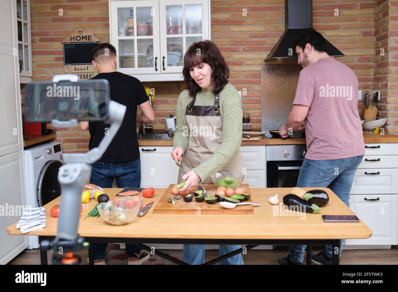 Trois amis cuisent et enregistrent une vidéo avec un smartphone pour leur chaîne de cuisson. Créateurs de contenu et influenceurs. Banque D'Images