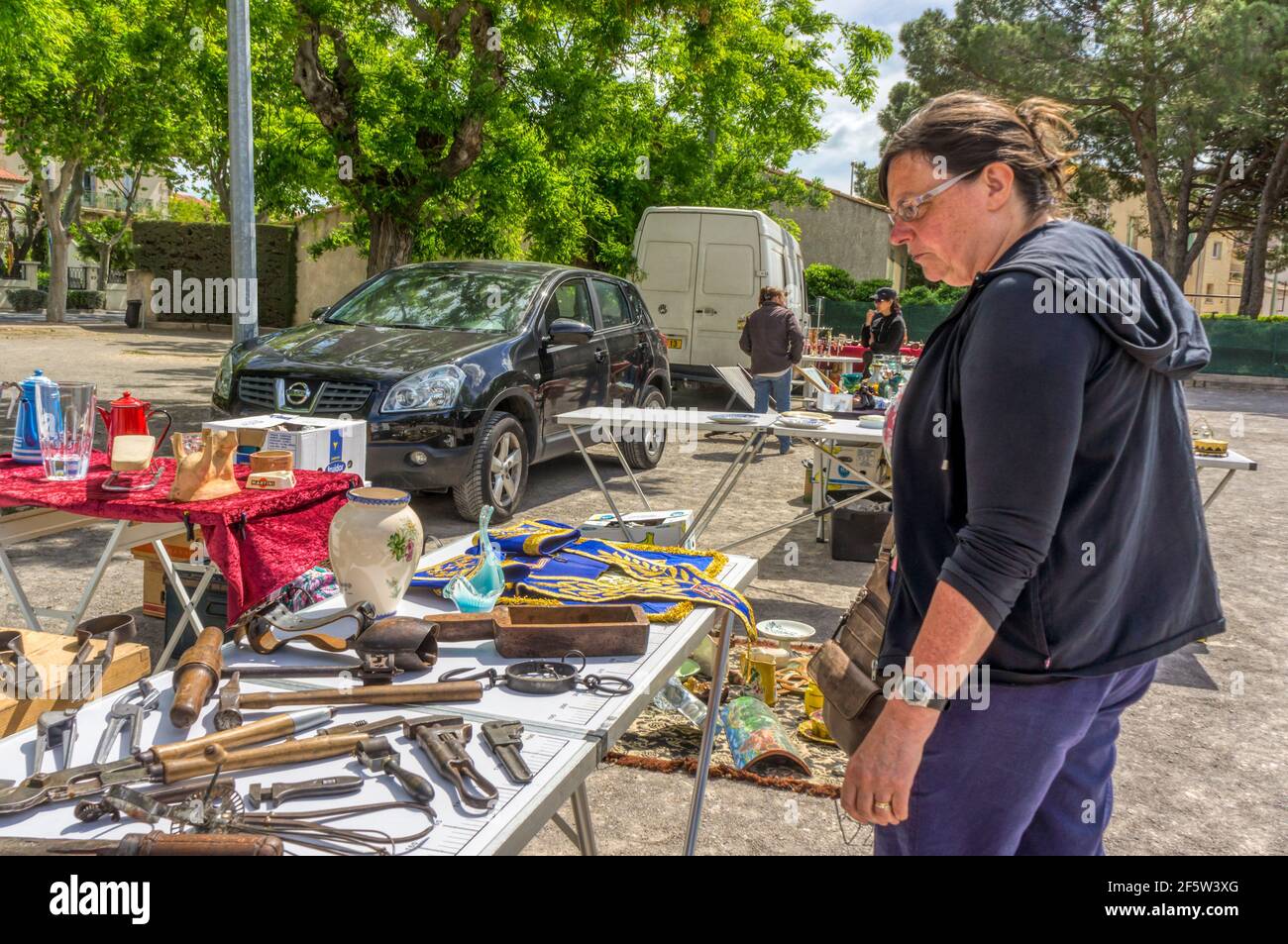 Femme en vacances à la recherche d'articles à vendre sur un marché aux puces dans la ville de Marseillan, dans le sud de la France. Banque D'Images