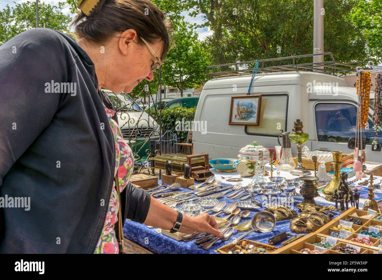 Femme en vacances à la recherche d'articles à vendre sur un marché aux puces dans la ville de Marseillan, dans le sud de la France. Banque D'Images