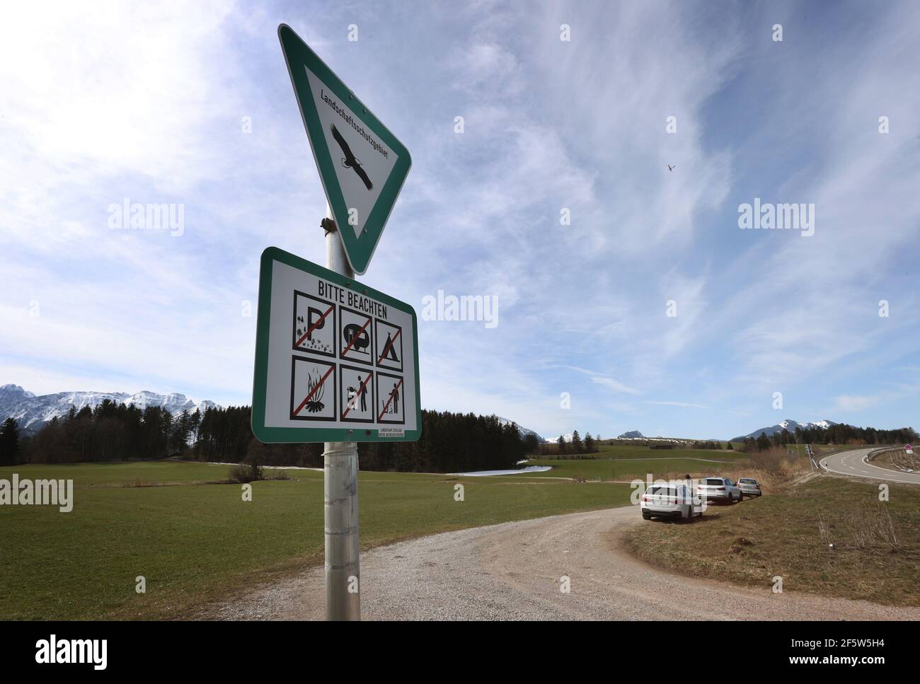 28 mars 2021, Bavière, Füssen: Un panneau devant les voitures garées indique une zone de conservation du paysage où le stationnement est interdit. De nombreuses personnes ont été attirées par le Hopfensee au soleil. Quelques-uns d'entre eux sont venus en voiture. Photo: Karl-Josef Hildenbrand/dpa - ATTENTION: Les plaques d'immatriculation ont été pixélisées pour des raisons juridiques Banque D'Images