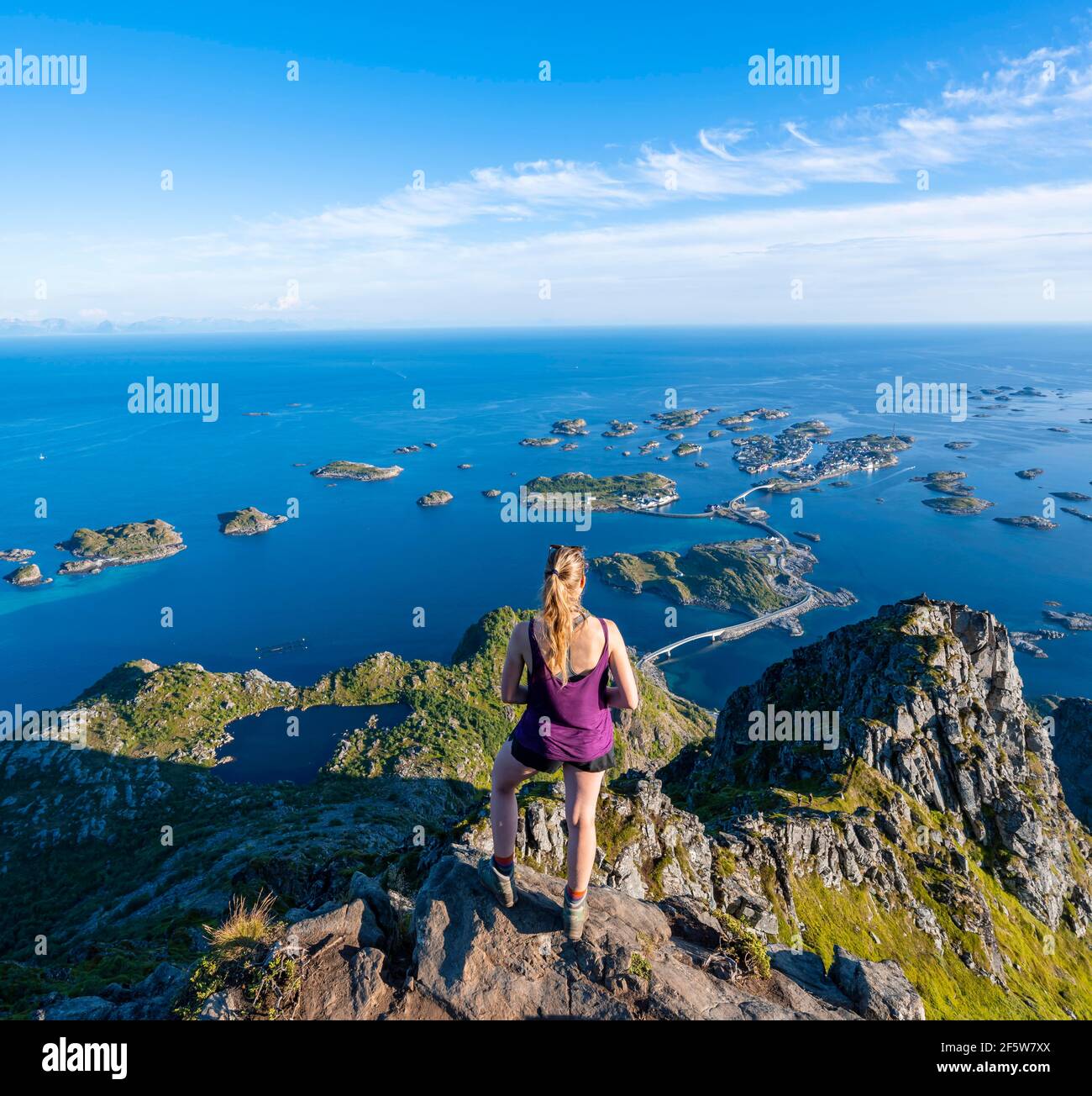 Lac Heiavatnet, maisons sur de petites îles rocheuses dans la mer, randonneur regardant du haut de la montagne Festvagtind à Henningsvaer, Vagan Banque D'Images