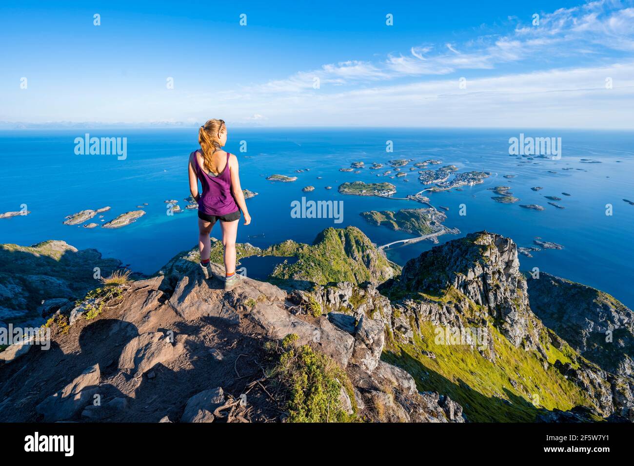 Petites îles rocheuses dans la mer, randonneur regardant du haut de la montagne Festvagtind au village Henningsvaer, Vagan, Lofoten, Nordland, Norvège Banque D'Images