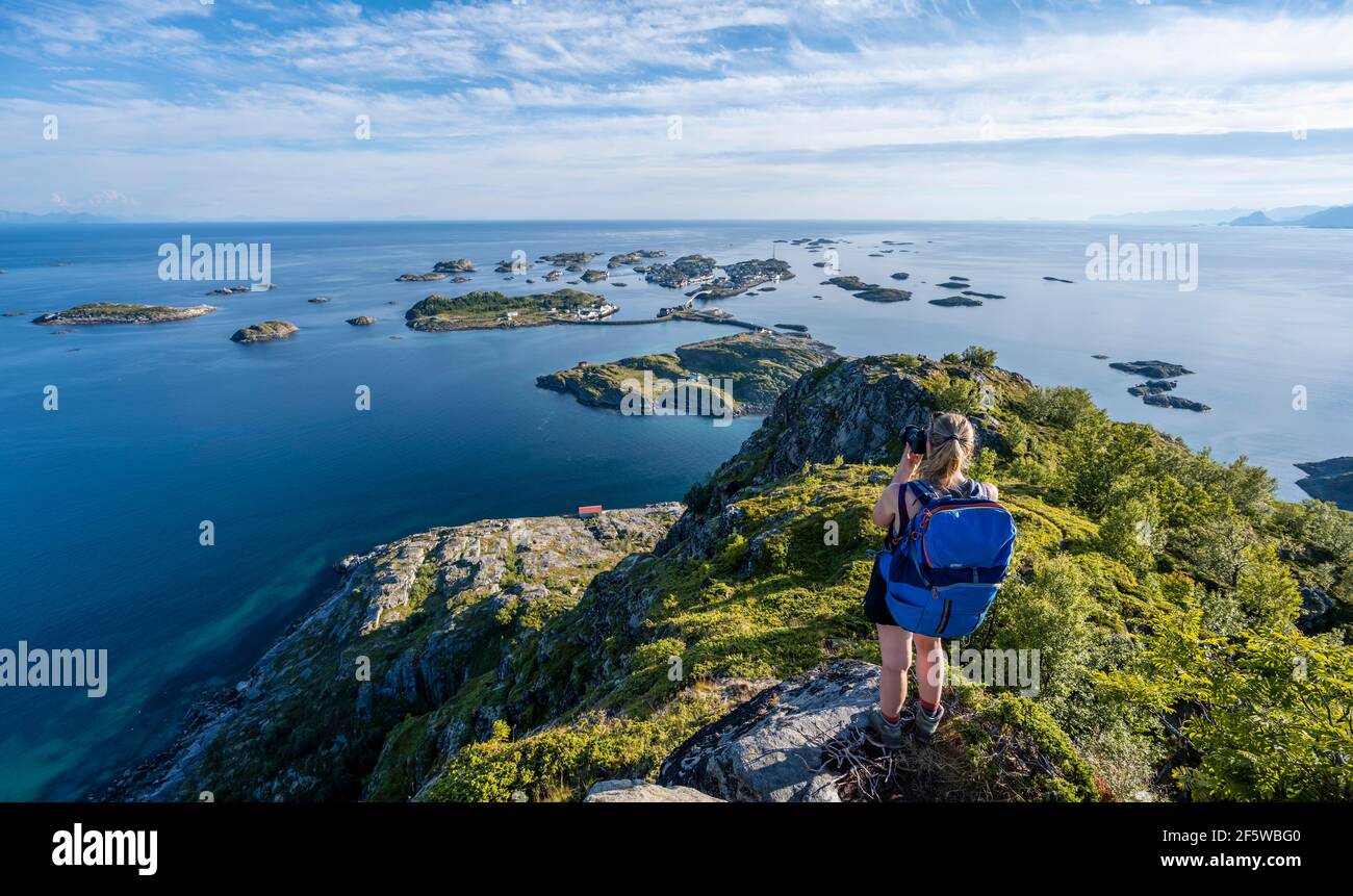 Maisons sur de petites îles rocheuses dans la mer, randonneur regardant sur Henningsvaer depuis le sommet de la montagne Festvagtind, Vagan, Lofoten, Nordland, Norvège Banque D'Images