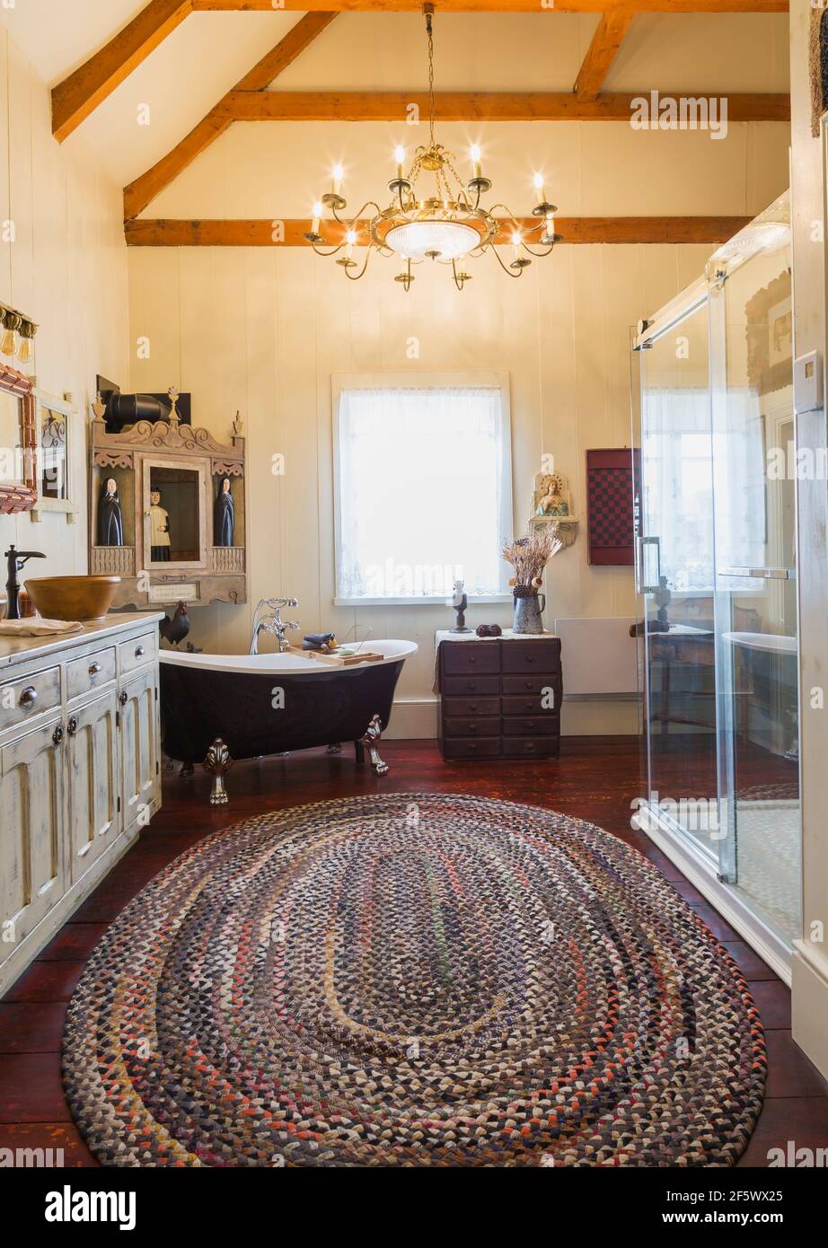 Armoire de magasin générale en bois antique blanchi avec deux lavabos moulés, baignoire à pied à griffe et cabine de douche en verre transparent avec carreaux en céramique bleu et blanc Banque D'Images