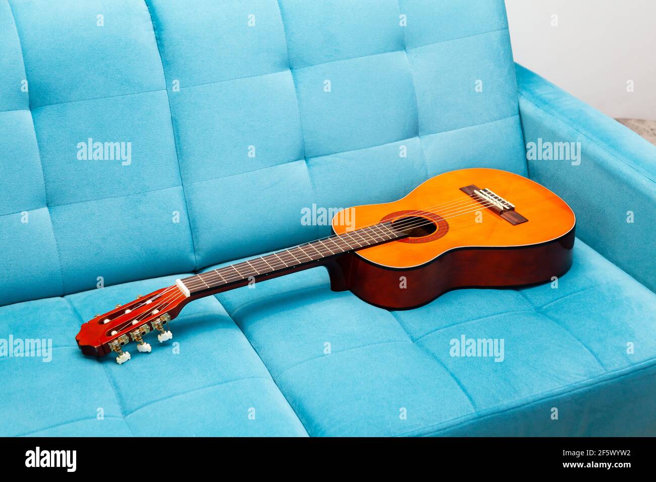Guitare classique posée sur un canapé bleu, laissée derrière, personne  autour, gros plan. Pratiquer un instrument de musique, apprendre à jouer de  la guitare, rester à la maison Photo Stock - Alamy