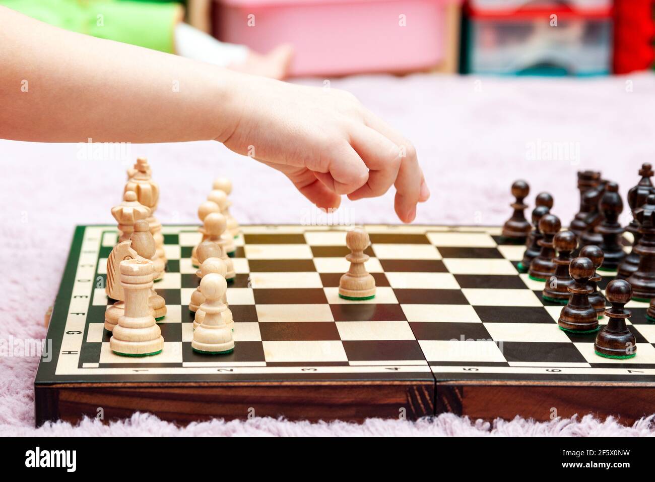 Jeune petite fille, enfant jouant aux échecs, chessboard vue latérale, main déplaçant une pièce d'échecs, sur le point de l'attraper, gros plan. Faire un mouvement, stratégie, planification, Banque D'Images