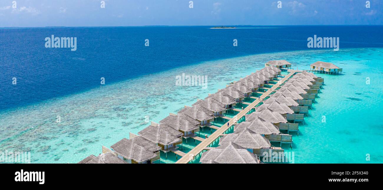 Vue aérienne sur l'île des Maldives, complexe de villas de luxe sur l'eau et jetée en bois. Magnifique ciel et océan lagon fond de plage. Vacances d'été Banque D'Images