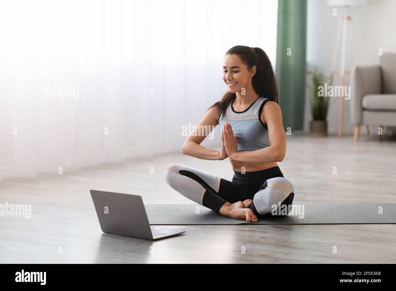Femme paisible méditant devant un ordinateur portable à la maison Banque D'Images