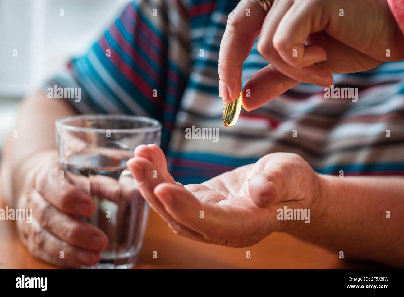 Infirmière donnant une capsule oméga-3 à une femme adulte âgée. Concept médical avec les mains des gens. Prendre des médicaments pour une bonne santé. Supplément nutritionnel huile de poisson Banque D'Images