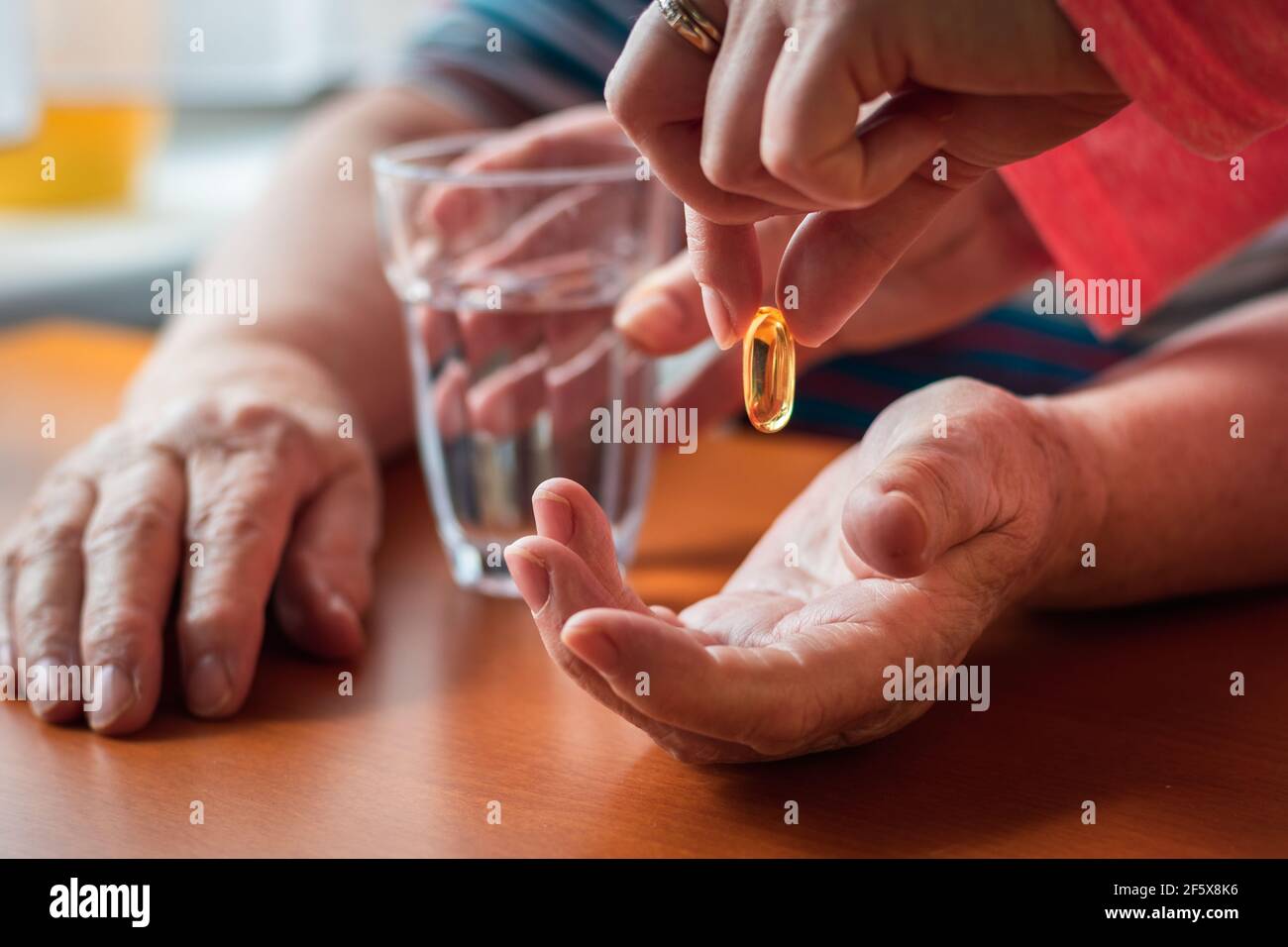 Infirmière donnant la pilule oméga-3 à une femme adulte âgée. Concept médical avec les mains des gens. Prendre des médicaments pour une bonne santé. Supplément nutritionnel Banque D'Images