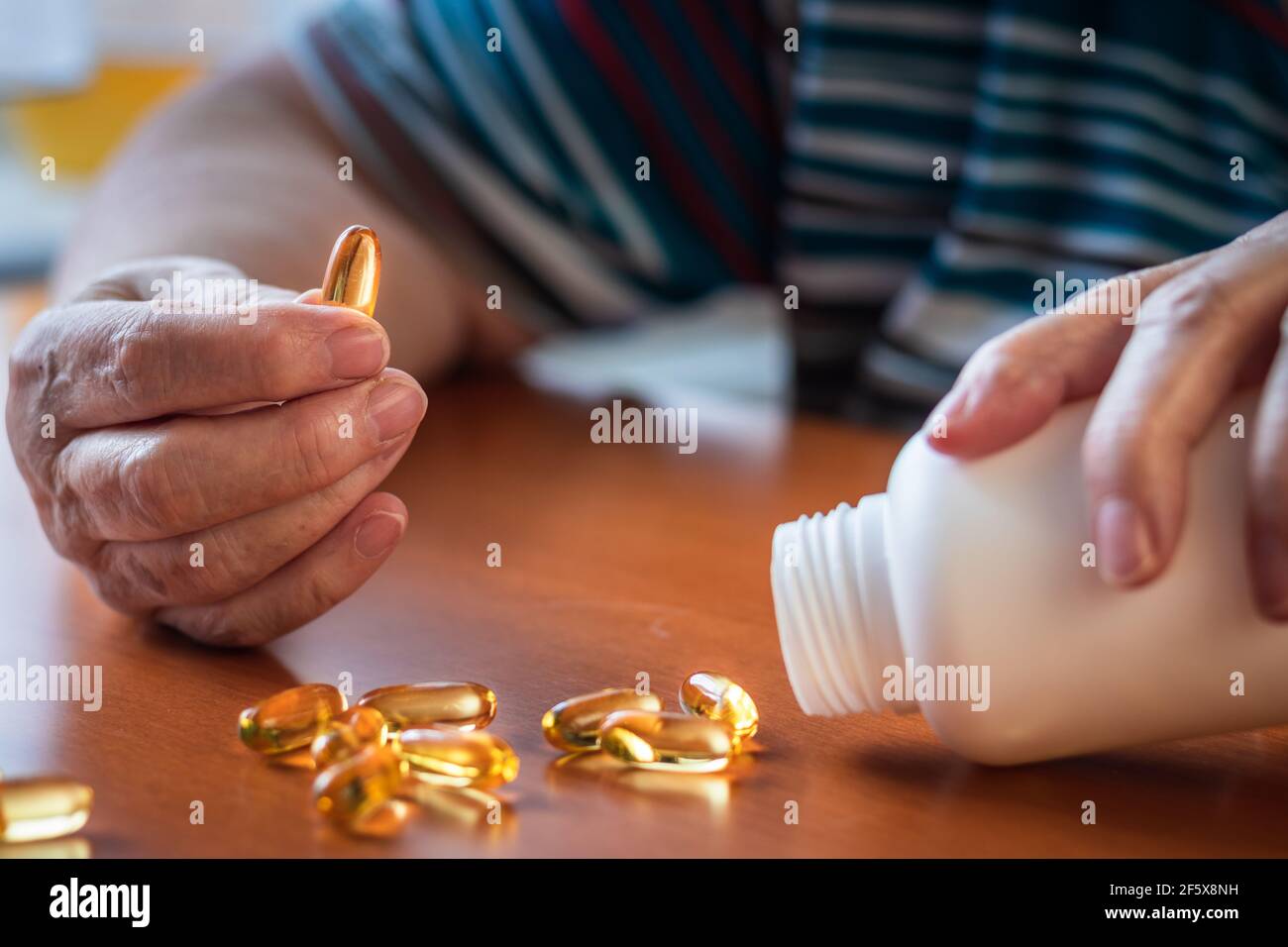 Femme âgée prenant une capsule d'oméga 3 du biberon. Concept médical et de soins de santé. Supplément alimentaire Banque D'Images