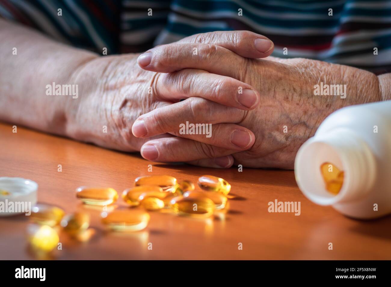 Vieilles mains de femmes et pilules omega-3 sur la table. Femme senior et supplément nutritionnel huile de poisson. Prendre des médicaments pour une bonne santé Banque D'Images